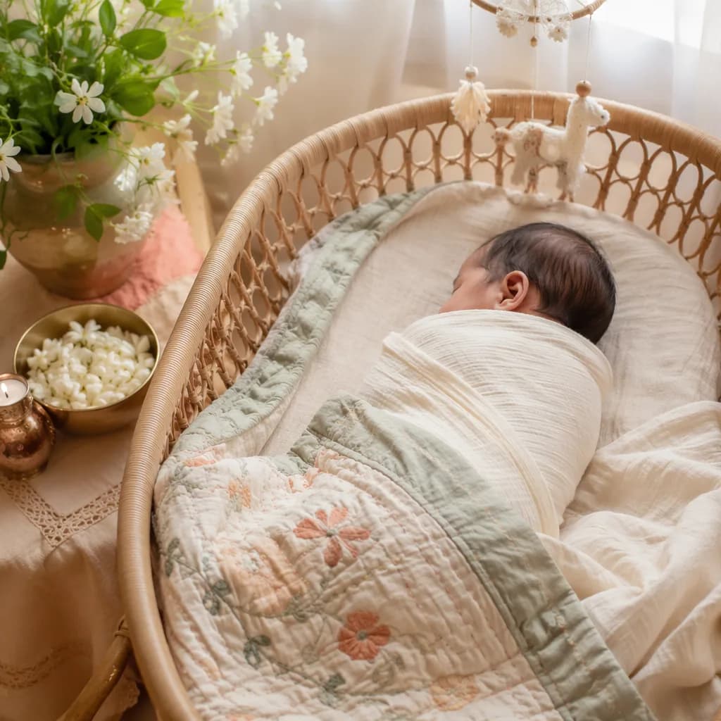 A peaceful Bengali newborn in a pastel nursery with a kantha quilt and soft natural light.